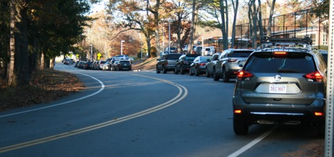 This figure is an image showing a line of private autos waiting on Downey Street to pick up students at dismissal time. The cars are waiting in the bicycle lane.